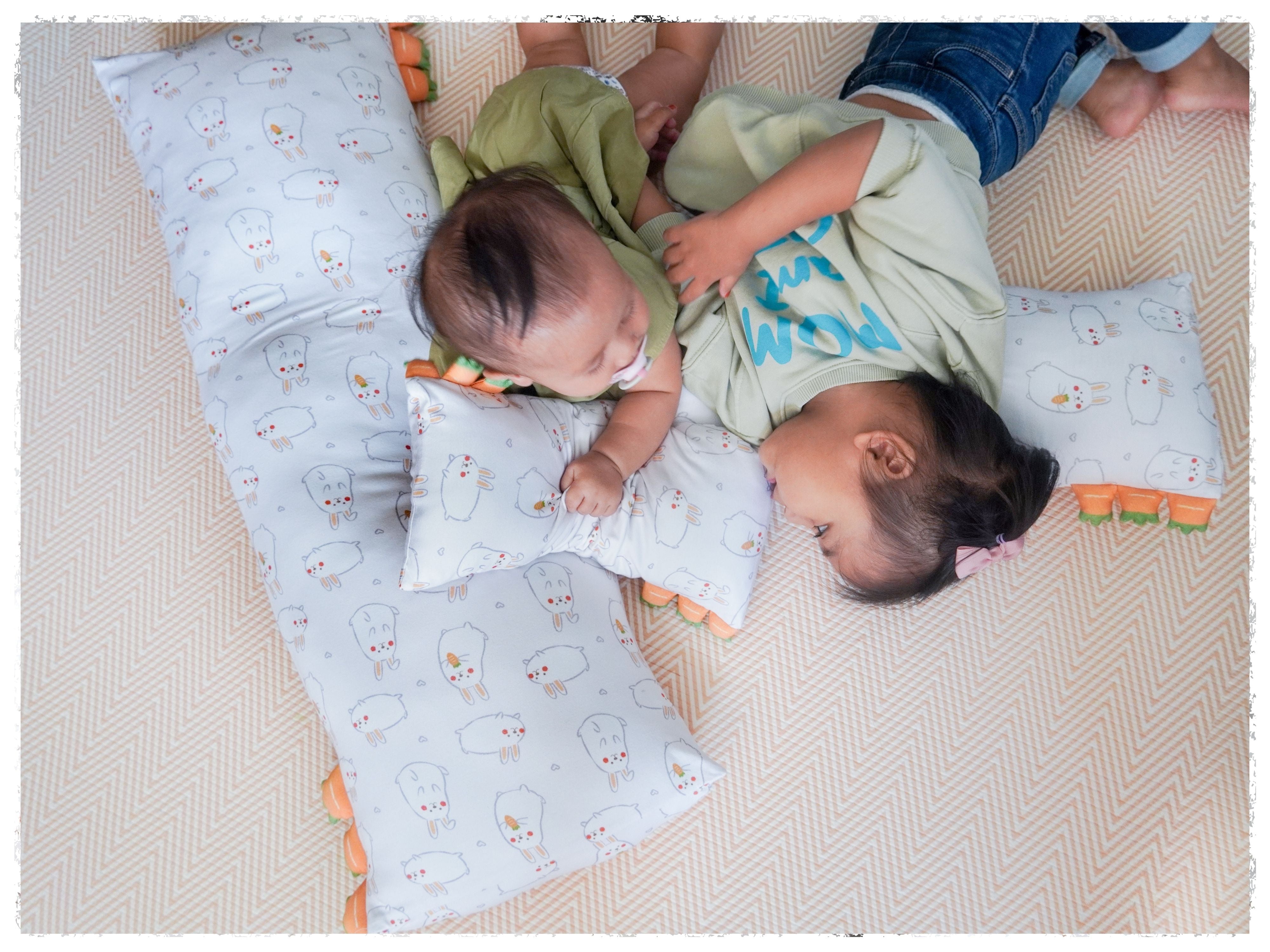 a pair of siblings lying down on some momo cho pillows